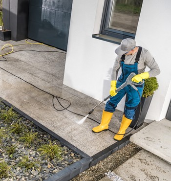 Mann beim Reinigen einer Terrasse mit dem Hochdruckreiniger